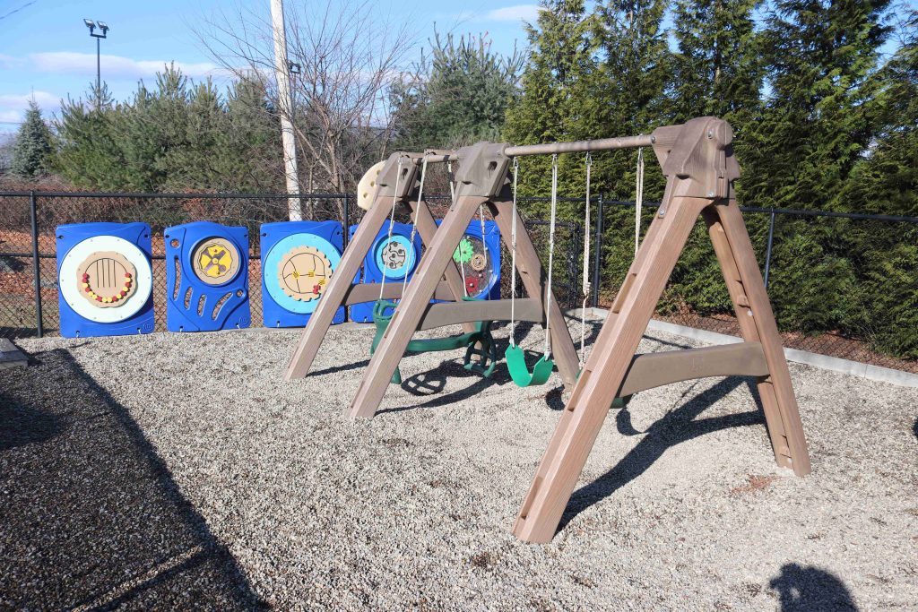 Wilmington TLC swing set in big playground with puzzle structures along the fence